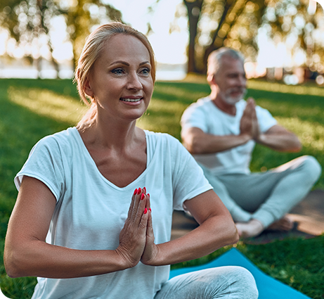 Woman sitting in the grass doing a yoga pose after her orthopedic surgeon recommended physical activity.