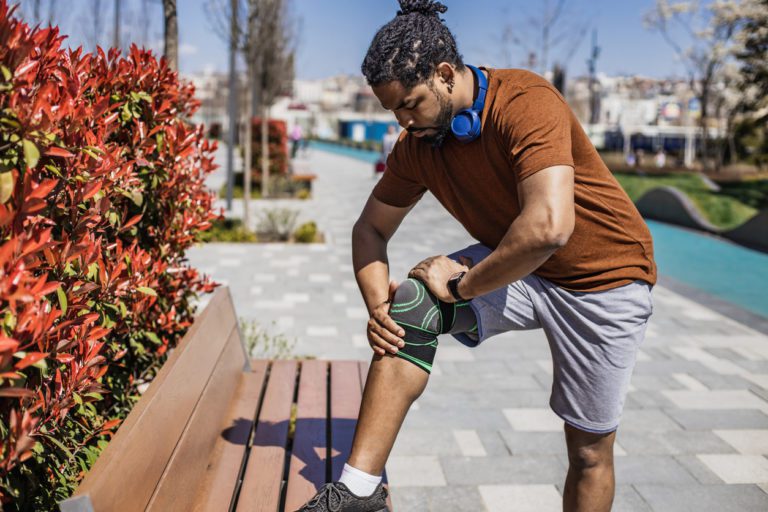 Young sportsman feeling knee pain while working out