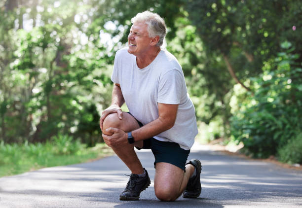 elder man experiencing knee pain on his right knee during a jog
