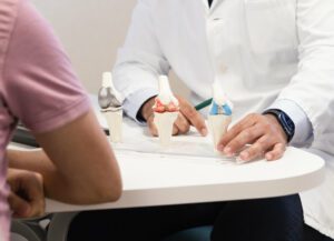 An orthopedic knee specialist is explaining knee health, implants, and the different types of knee replacements available to a patient.