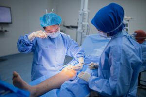 A female doctor is stitching a patient's knee wound after arthroscopic surgery for a torn meniscus.