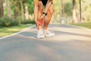 A young adult male is experiencing leg pain due to shin splints while running.