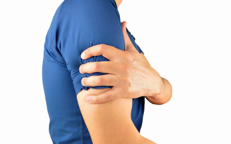 A young man is holding his shoulder in pain due to a dislocated shoulder injury.