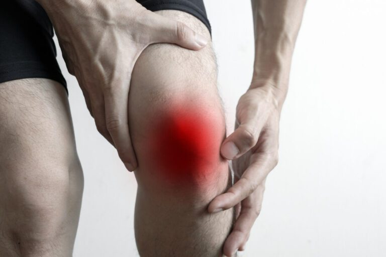 A man puts his hands on his knees due to knee pain.