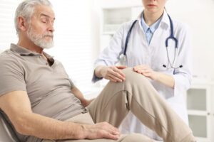 Knee doctor examining a senior patient with knee pain in hospital.
