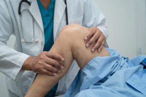 A knee specialist examining, massaging, and treating a patient suffering from knee pain.